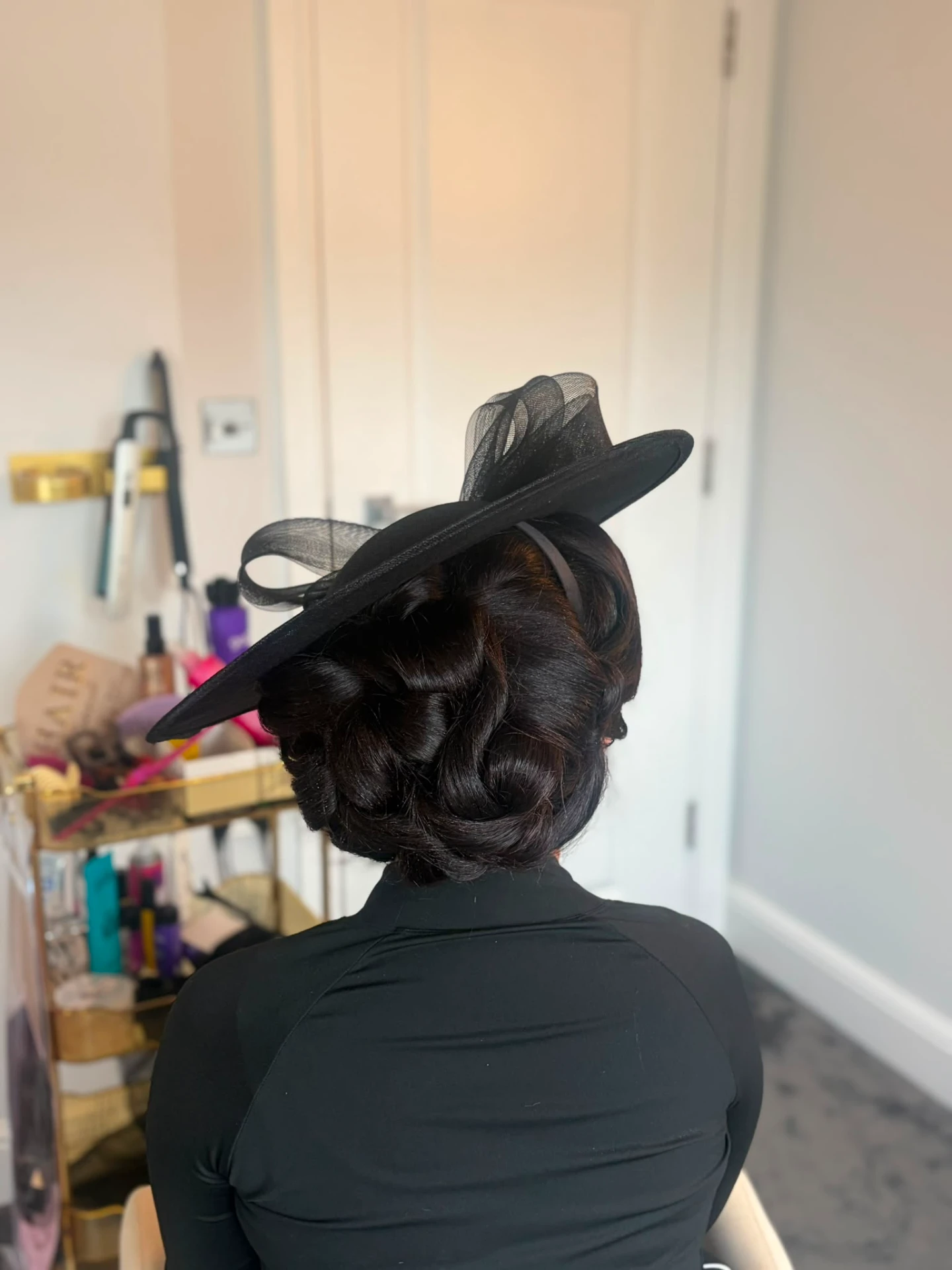 Vintage pin-curl updo with black occasion hat